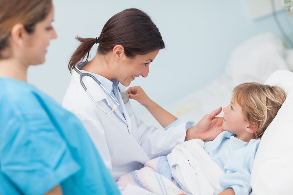 Child touching stethoscope of a doctor in hospital ward