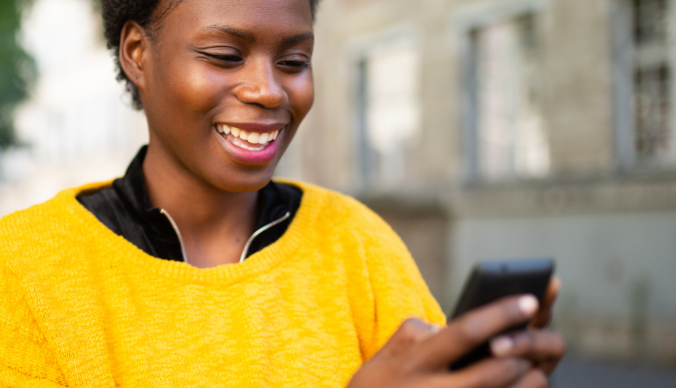 african-american-women-yellow-sweater-on-device-cell-phone-smiling-happy