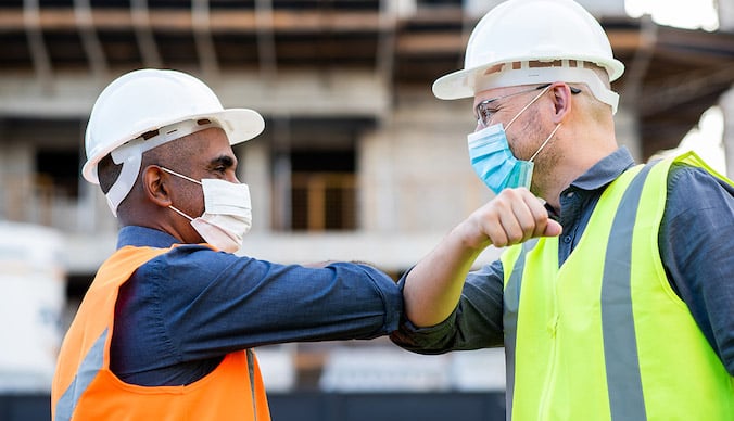 construction-workers-elbow-bump-covid-masks-manufacturing